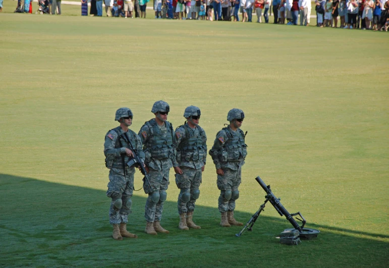 military personnel stand on the grass to observe soing