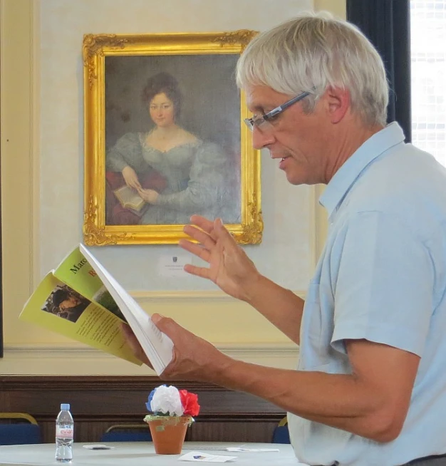 a man is reading a book in front of an oil painting