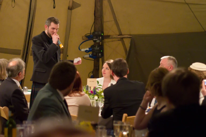 a group of people sitting around tables while a man eats