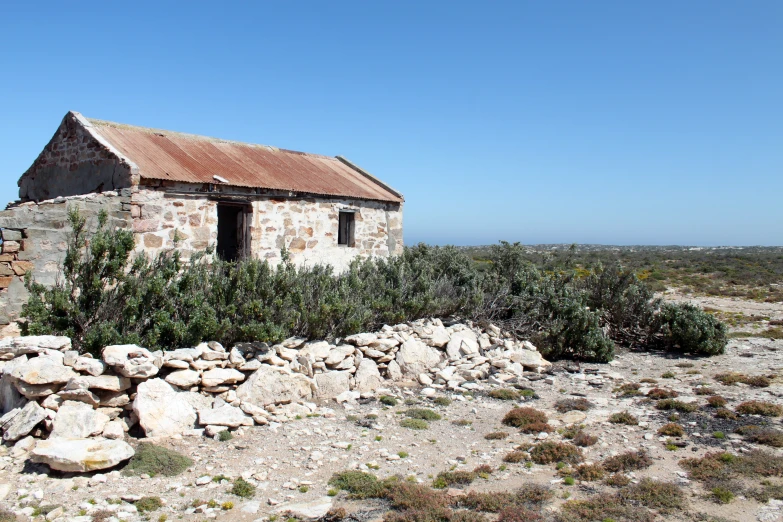 a old house with no roof and a few vegetation around it