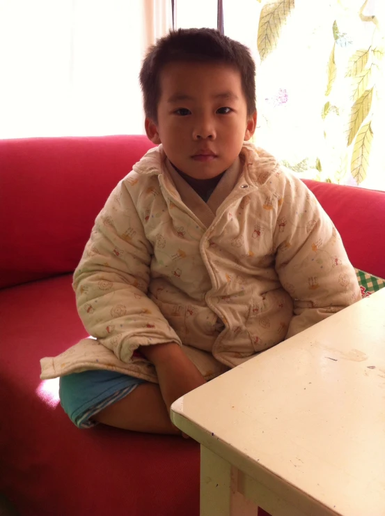 a child sitting on a couch near a table