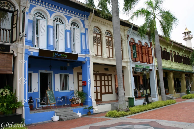 a row of buildings on a street next to palm trees