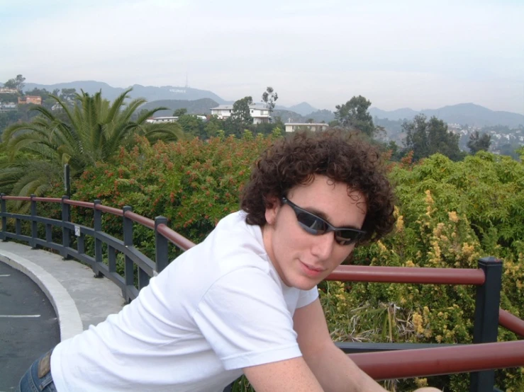 young man with sunglasses leaning up on rail