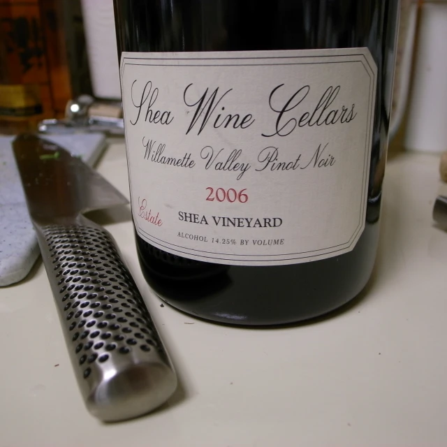 wine bottle with label sitting on table next to grater