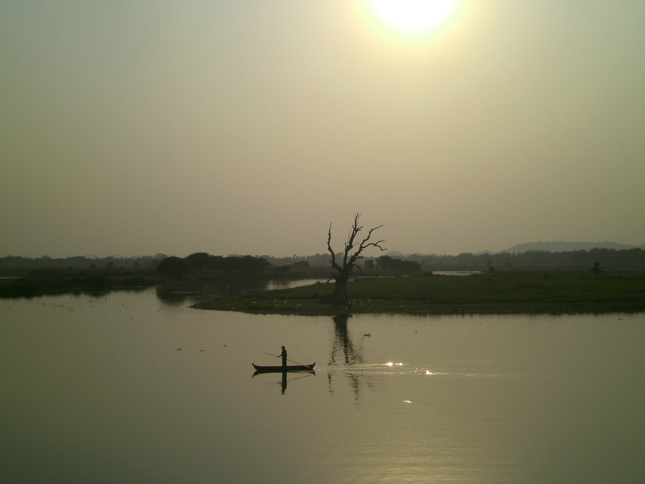 a lone man paddling a canoe down the lake