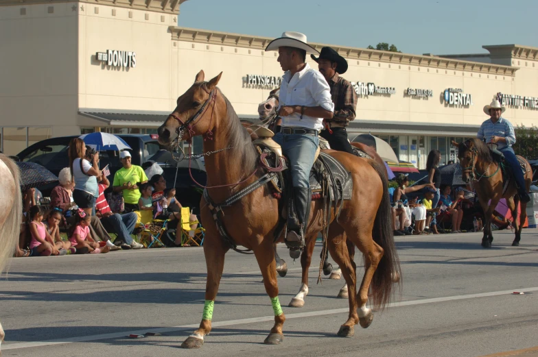 two men on horses in the street with people watching