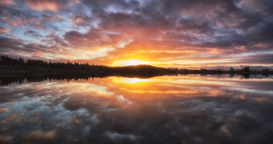 the sunset lights up the sky above water