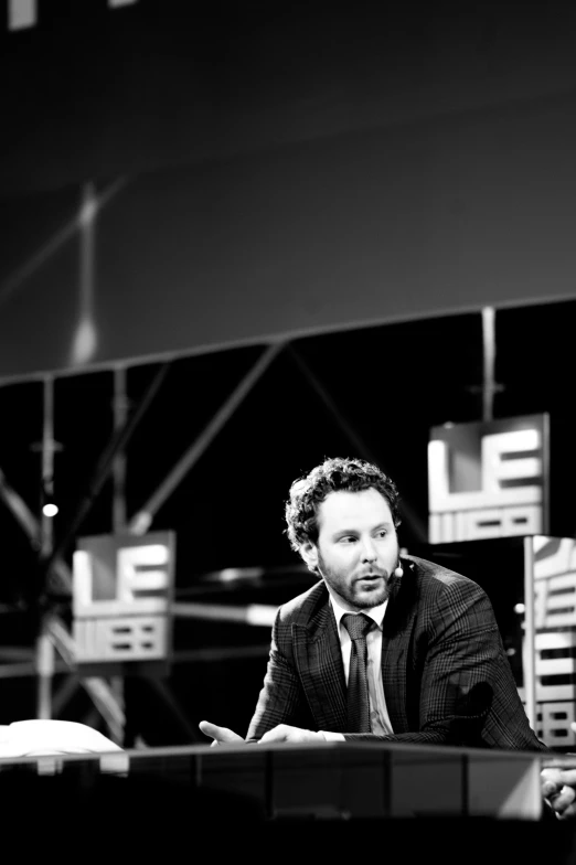 a man in a suit is speaking at a table