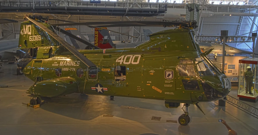 two green military style helicopters sitting inside a museum