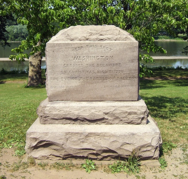 a stone monument sits in front of a pond