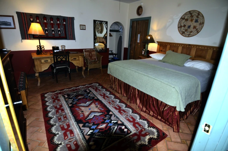 a bed room with a neatly made bed and a red rug