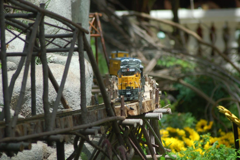 a toy train traveling down the tracks near a forest