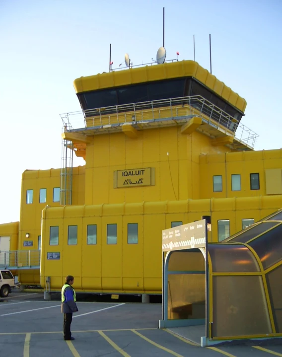 a man in the foreground standing in front of a yellow control tower