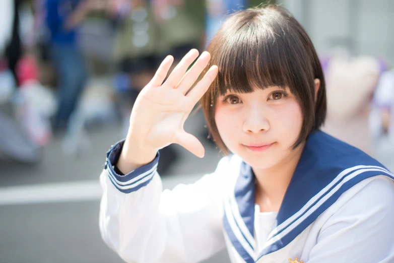 a woman in blue jacket holding a hand up in front of her