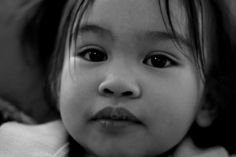 a black and white image of a little girl with a scarf around her neck