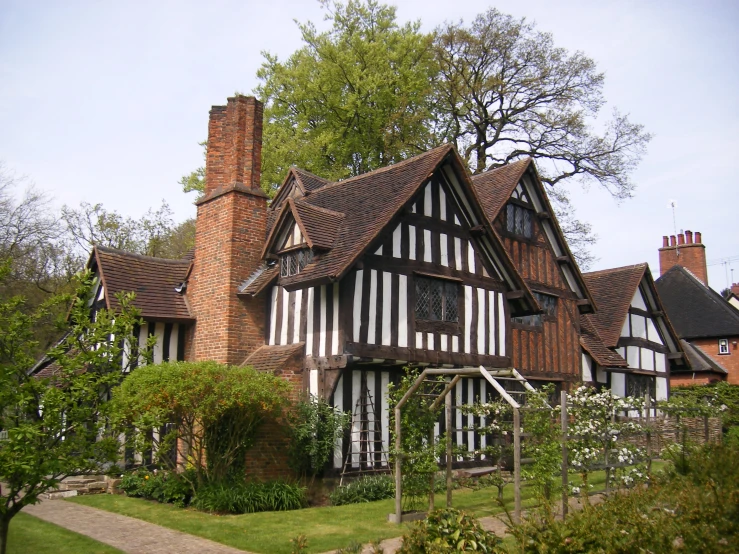 a home with an outside walkway, bushes and trees