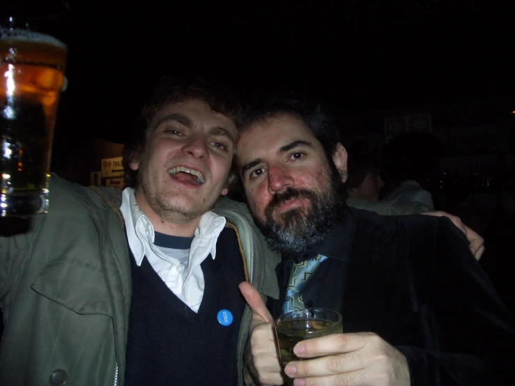 two men pose together in a dark bar