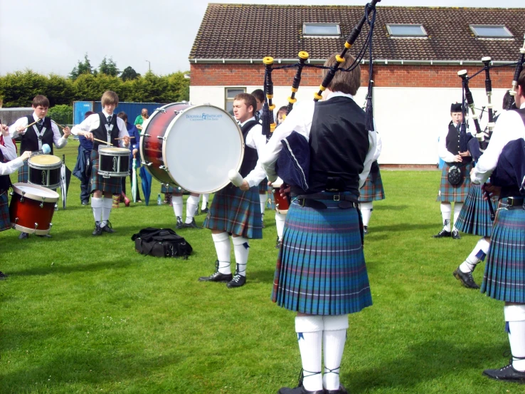 a group of men in scottish clothing play drumbeats