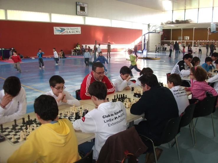 a group of young men play chess in an indoor setting