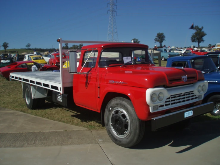 a very old red truck sitting next to other old cars