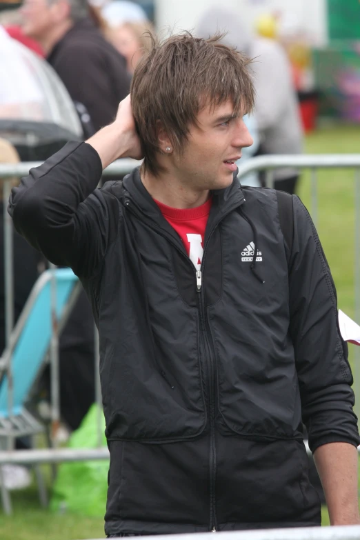 a male with a black jacket on standing near the fence