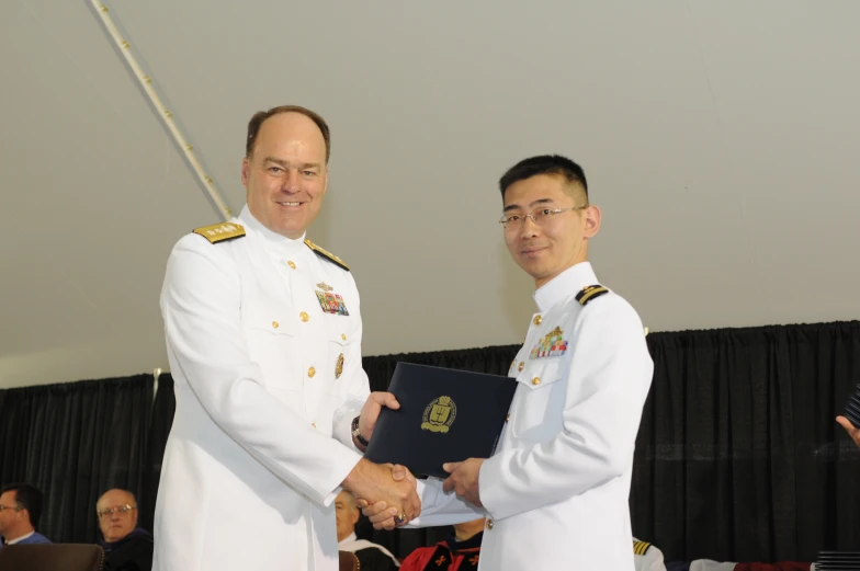 two men shaking hands while another man looks on