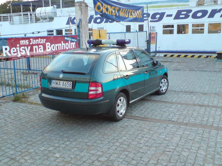 a green taxi car parked in front of a boat