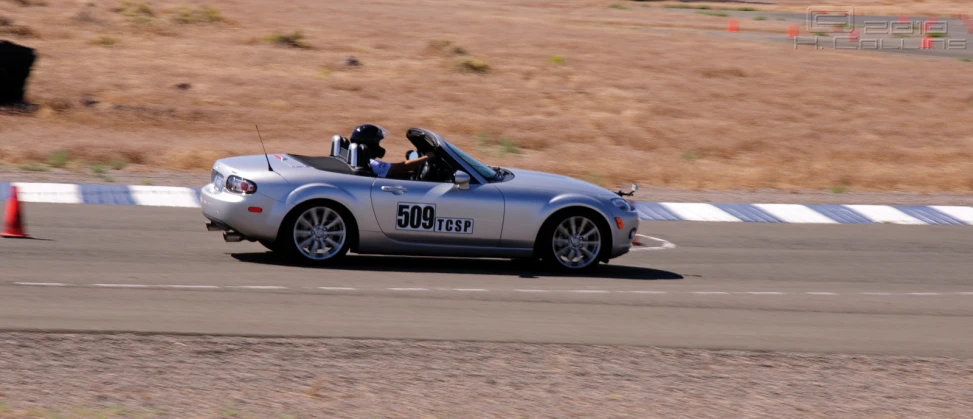 a silver convertible car driving along the road