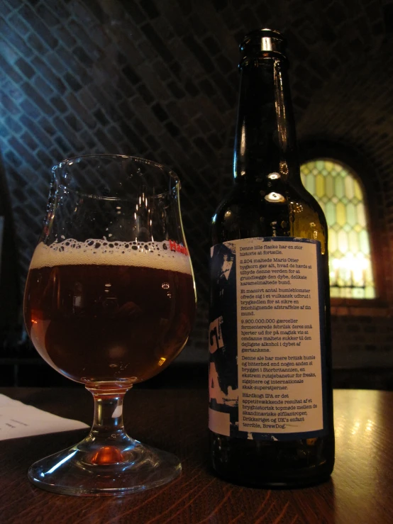 a glass filled with dark brown ale next to a beer bottle