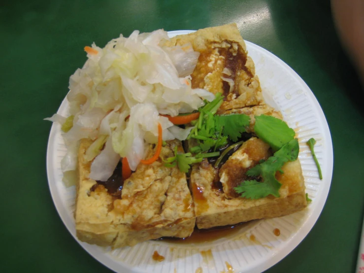 two tofu slices with vegetables and sauce on top of a white plate