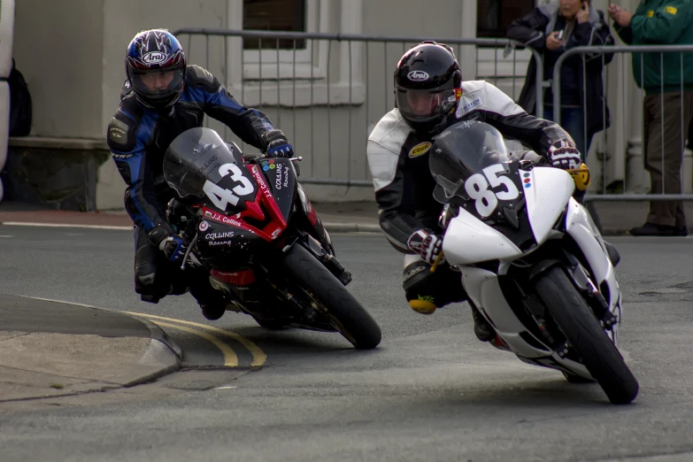 two motorcycle racers are racing their motorcycles down the street