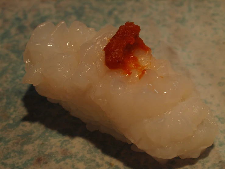 there is a piece of white sushi with sauce on it