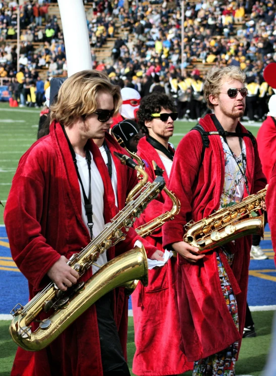 a group of men in red marching outfits and one wearing an orange band uniform