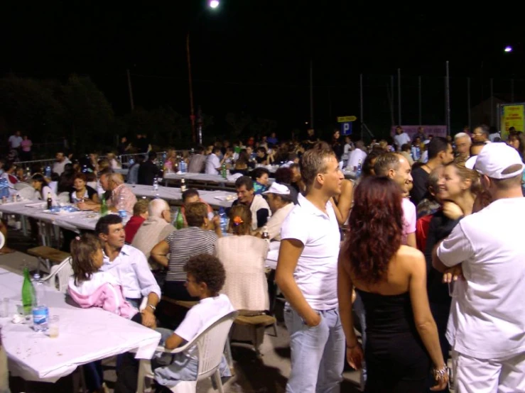 a group of people is eating outside at night