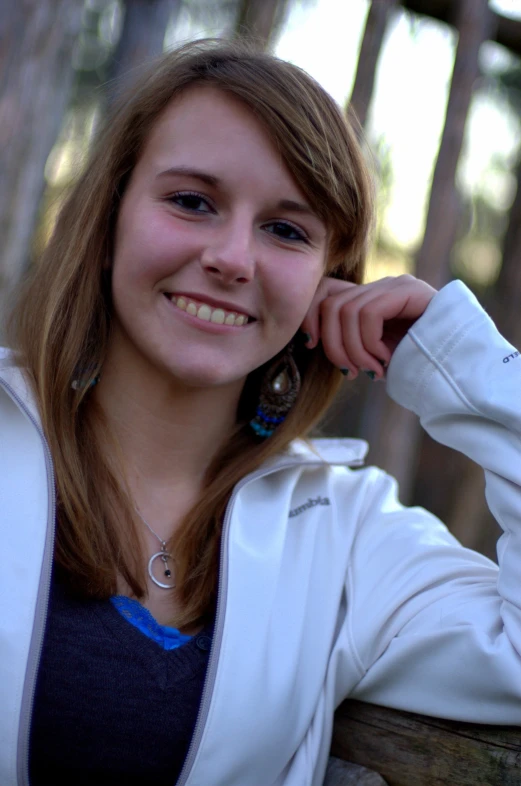 a girl wearing an earring that is resting her hand on the neck