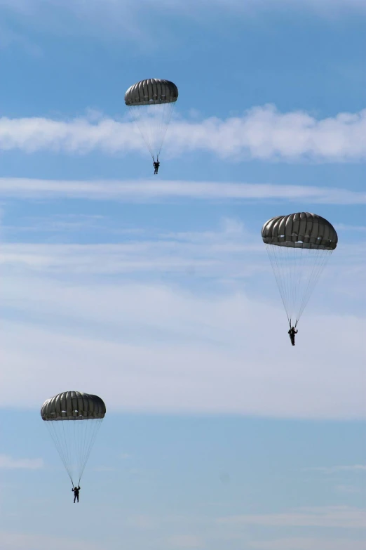 three parachutes flying in the air during a sunny day