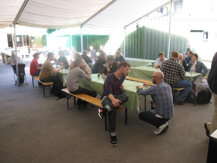 some guys eating together outside near a large tent