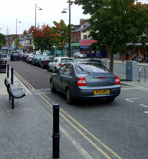 cars are driving down the street behind a bench