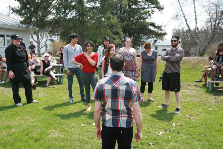 many people standing in the grass talking and enjoying