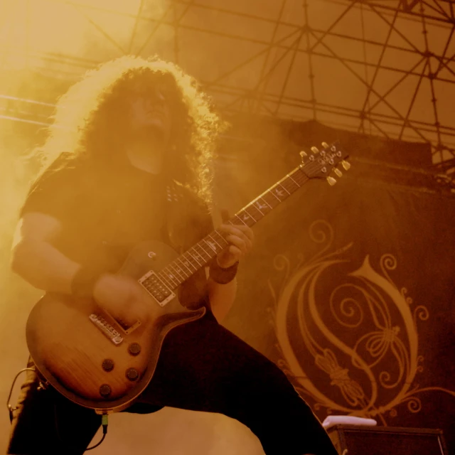 a woman is playing an electric guitar while stage lights shine on her