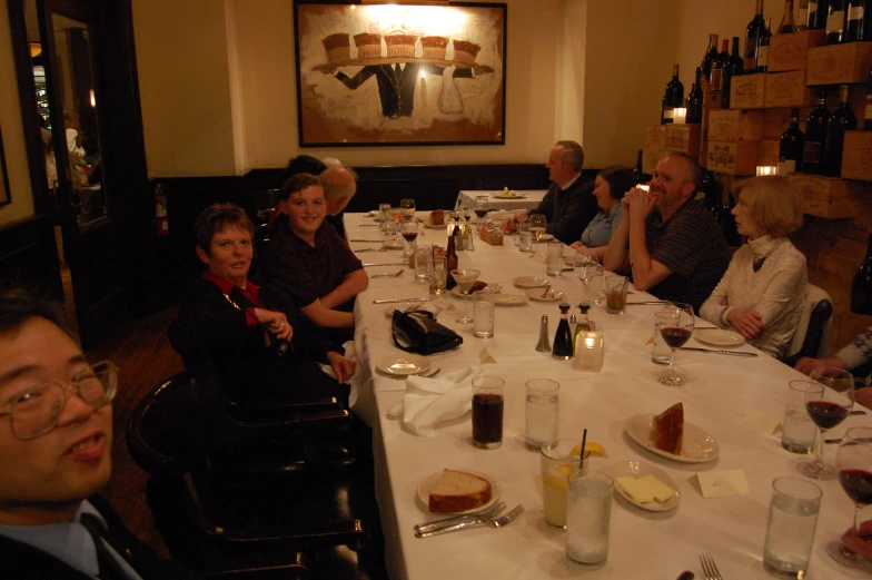 several people are seated at a dining table with drinks on it
