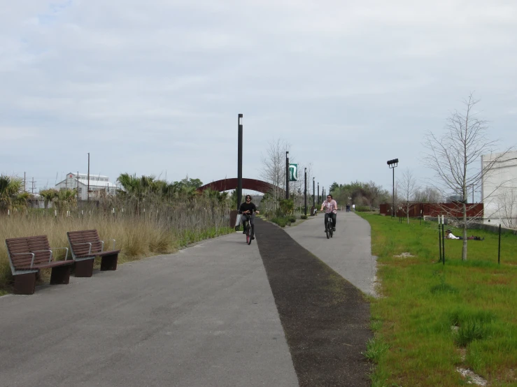 three bicyclists ride down a paved walkway