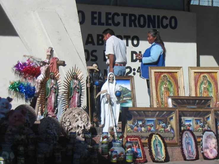 a statue of the virgin mary next to art on display in front of a building