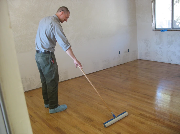 man on floor mop looking at wall with bare walls