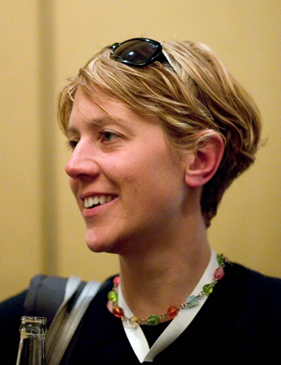 a smiling blond woman with a bottle of beer