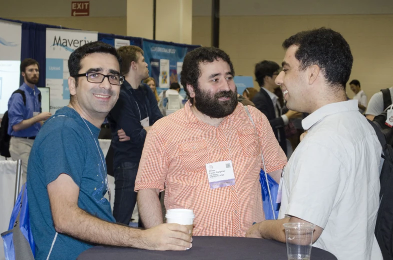 three men standing around a table with drinks in their hands