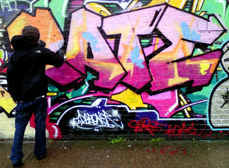 a man is standing near a wall with graffiti