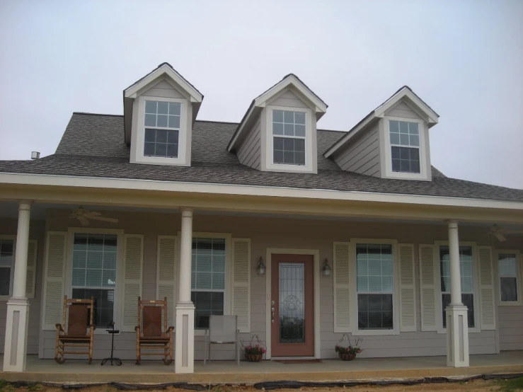 a small two story house with front porch, front lawn, and covered patio