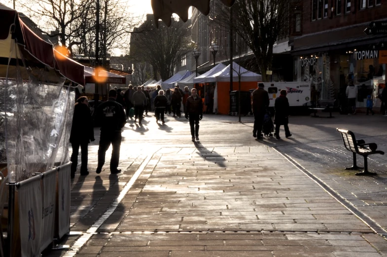 a group of people walking down the street next to shops