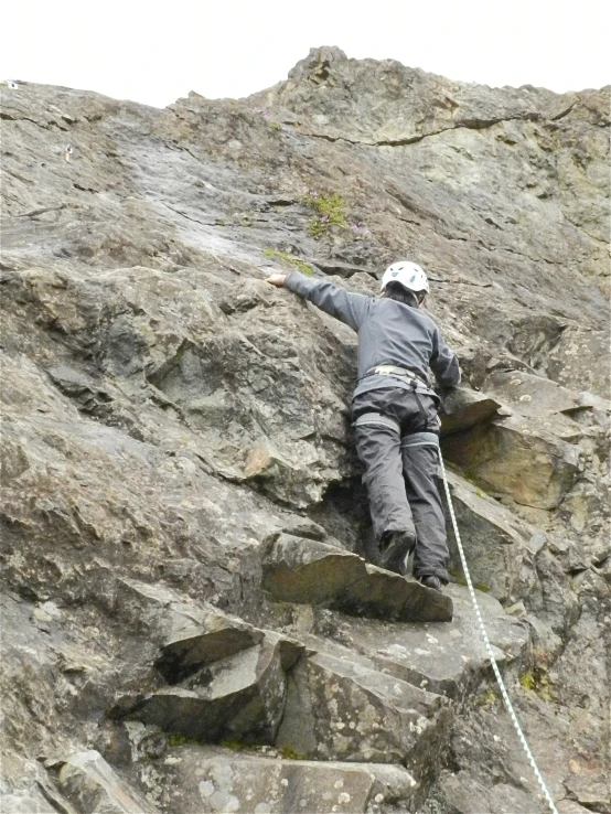 a man with a safety harness, climbing up a mountain